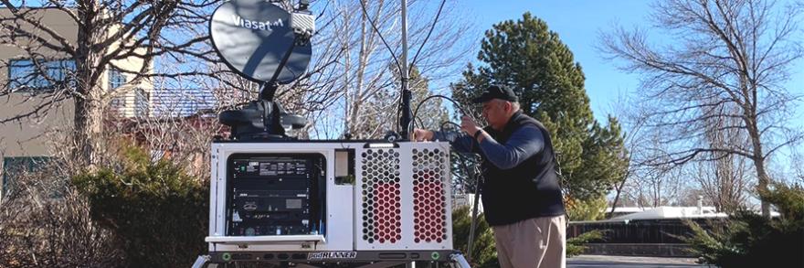 A person sets up a FirstNet compact rapid deployable in a parking lot