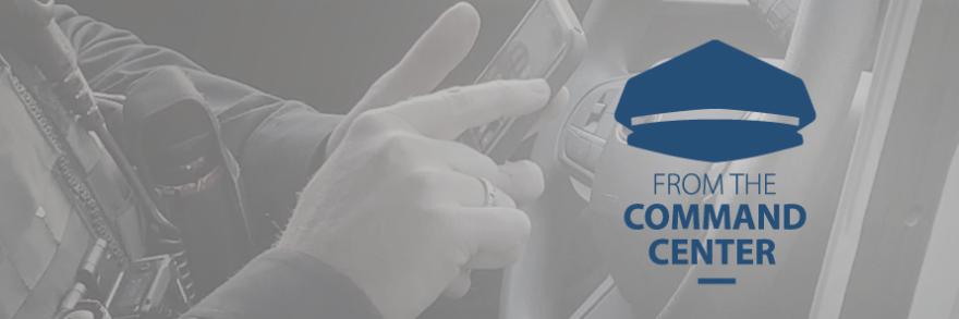 A police officer using a smartphone in the front seat of a patrol vehicle