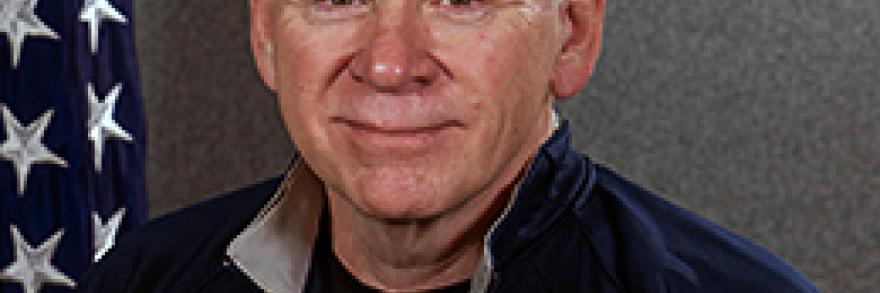 Headshot of John Hunt. He sits in front of an American flag.