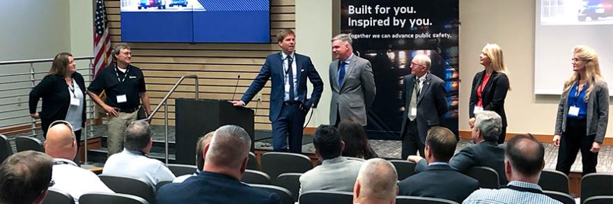 Members of the FirstNet Authority team stand facing a seated crowd of public safety professionals. 