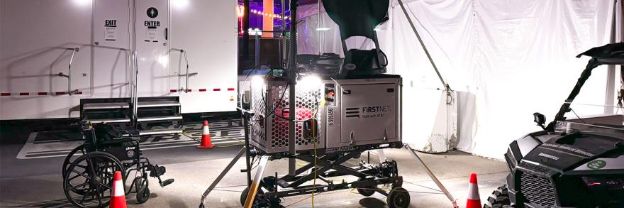 A FirstNet Compact Rapid Deployable set up near medical tents at the Electric Daisy Carnival. Trailer, wheelchair, side-by-side vehicle, and orange cones. 