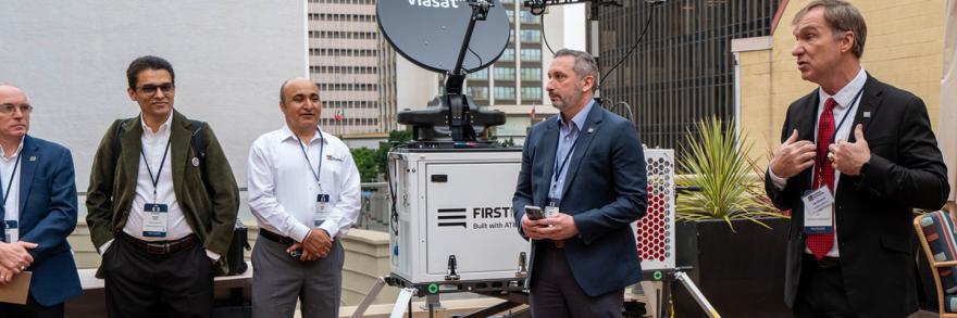 Joe Wassel, FirstNet Authority CEO, speaks to staff at 5x5 standing in front of a Compact Rapid Deployable. 