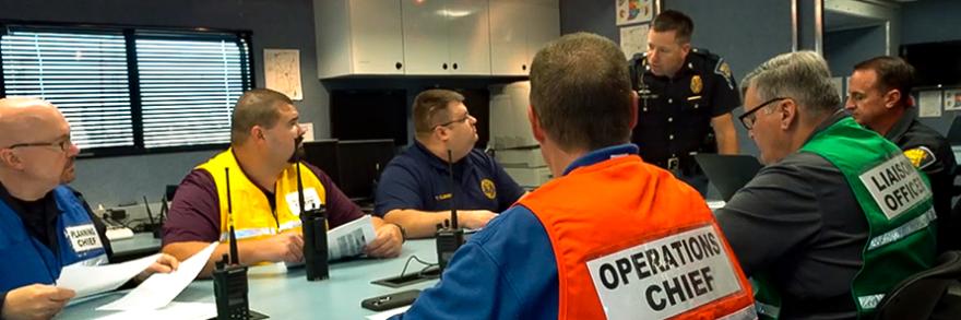 Emergency management and public safety professionals sit around a conference table in discussion.
