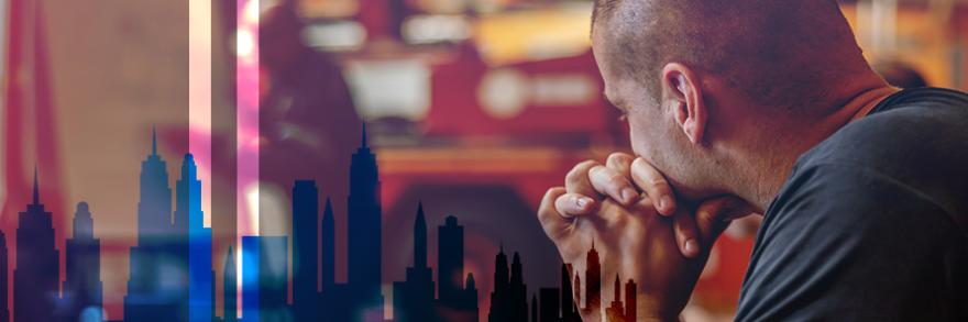 First responder somberly looking away; silhouette of New York City skyline with World Trade Center tower remembrance silhouettes