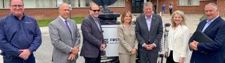 Rhode Island state government, emergency management, FirstNet Authority, and AT&T personnel stand in front of a portable cell site known as a Compact Rapid Deployable.