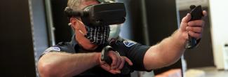 First responder wearing virtual reality glasses and holding controllers and gesticulates forward.