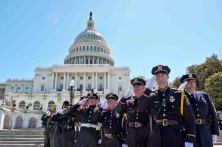Nine police officers salute with the capitol building behind them during National Police Week 2017 in Washington DC. 