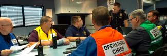 Emergency management and public safety professionals sit around a conference table in discussion.
