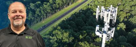 In the background, a rural road cuts through a dense forest with a cell tower rising above the treetops; on the left, West Virginia Department of Transportation Assistant Secretary Scott Eplin smiles.