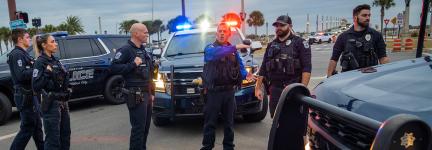 Six police officers talking in front of three police vehicles at an intersection in St. Augustine, Florida