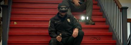 A police officer participating in the drone competition uses First-Person View (FPV) goggles and a remote control to maneuver a drone from a stairwell inside a Nashua middle school.
