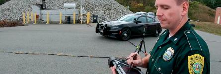 A New Hampshire State Police trooper uses a tablet to monitor and steer a drone