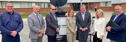 Rhode Island state government, emergency management, FirstNet Authority, and AT&amp;T personnel stand in front of a portable cell site known as a Compact Rapid Deployable.